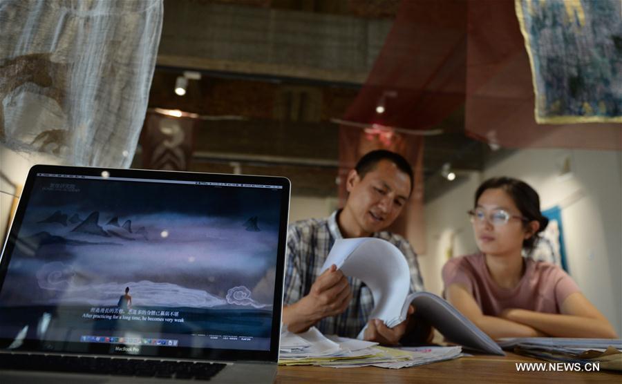Chen Haitao (L), a member of the designing team with the Dunhuang Academy, works with his colleague in Dunhuang, northwest China\'s Gansu Province, Sept. 18, 2016. Dunhuang Academy has been working on making animated shows out of ancient Dunhuang murals using modern digital media in recent years. Two films based on murals in Cave No. 254 of Mogao Grottoes have been completed. (Photo/Xinhua)