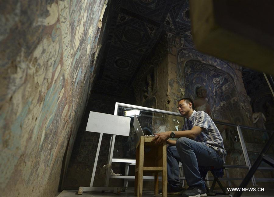 Chen Haitao, a member of the designing team with the Dunhuang Academy, works at Cave No. 254 in Mogao Grottoes, Dunhuang, northwest China\'s Gansu Province, Sept. 18, 2016. Dunhuang Academy has been working on making animated shows out of ancient Dunhuang murals using modern digital media in recent years. Two films based on murals in Cave No. 254 of Mogao Grottoes have been completed. (Photo/Xinhua)
