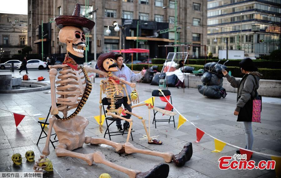 A couple take pictures with fake giant skeletons placed in an altar in front of the Fine Arts Palace, in the framework of the Day of the Dead, in Mexico City on November 1, 2016.Mexicans who culturally celebrate and revere death begin to honour their deceased loved ones in the three-day Day of the Dead festivities.(Photo/Agencies)