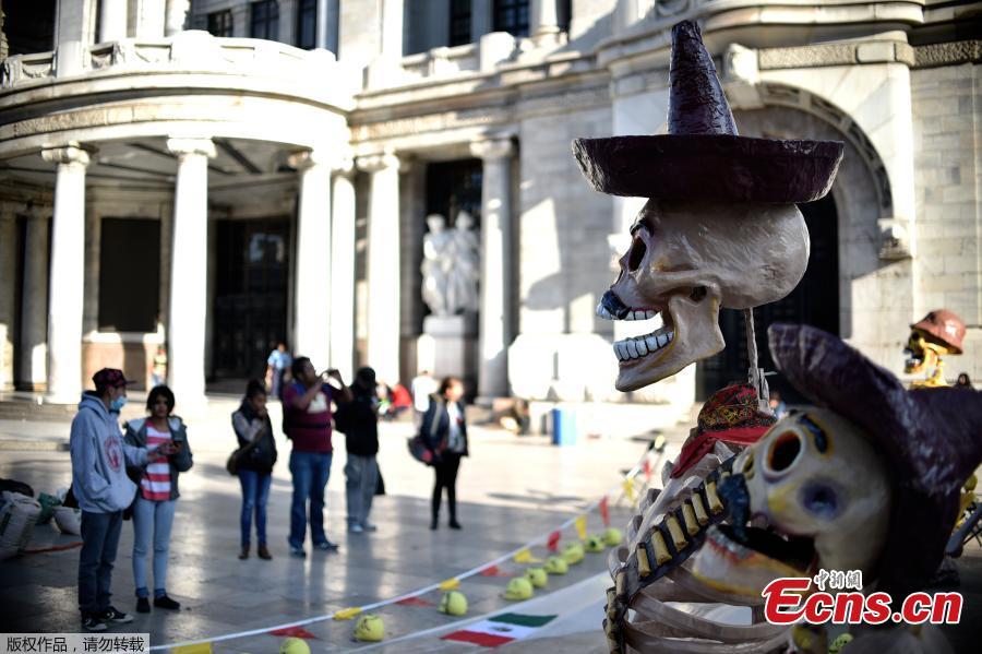 People observe fake giant skeletons placed in an altar in front of the Fine Arts Palace, in the framework of the Day of the Dead, in Mexico City on November 1, 2016. Mexicans who culturally celebrate and revere death begin to honour their deceased loved ones in the three-day Day of the Dead festivities.(Photo/Agencies)