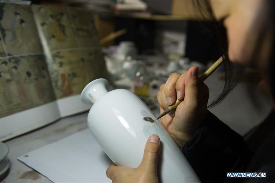 Artist Li Caixia creates traditional literati painting on a porcelain at the workshop in Jingdezhen, east China\'s Jiangxi Province, Dec. 23, 2016. (Xinhua/Weng Xinyang)