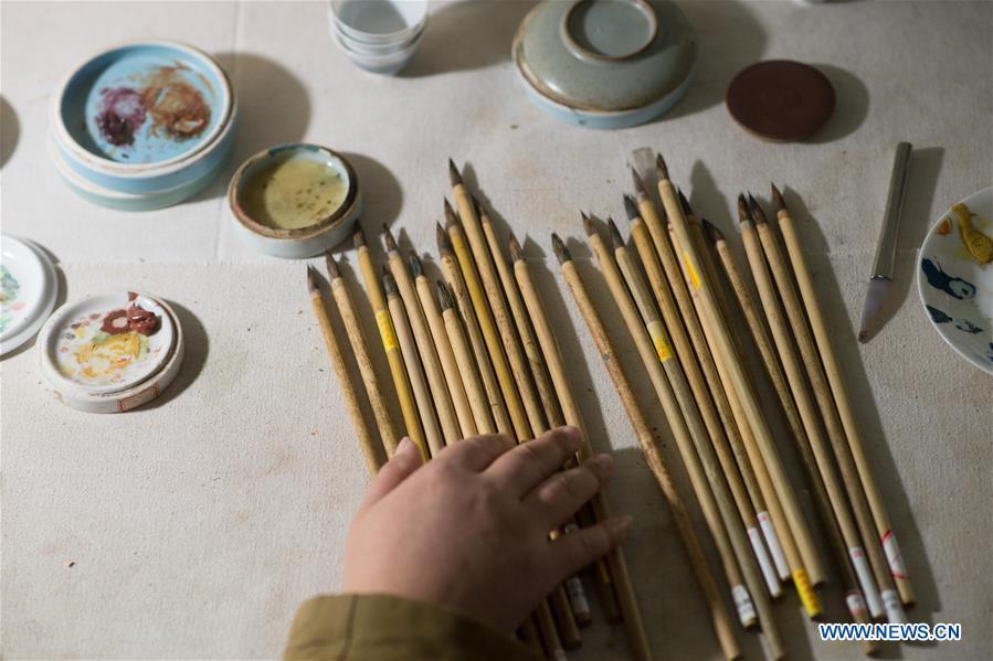 Artist Xiang Zhengyi selects brushes for traditional literati painting on porcelain at the workshop in Jingdezhen, east China\'s Jiangxi Province, Dec. 23, 2016. (Xinhua/Weng Xinyang)