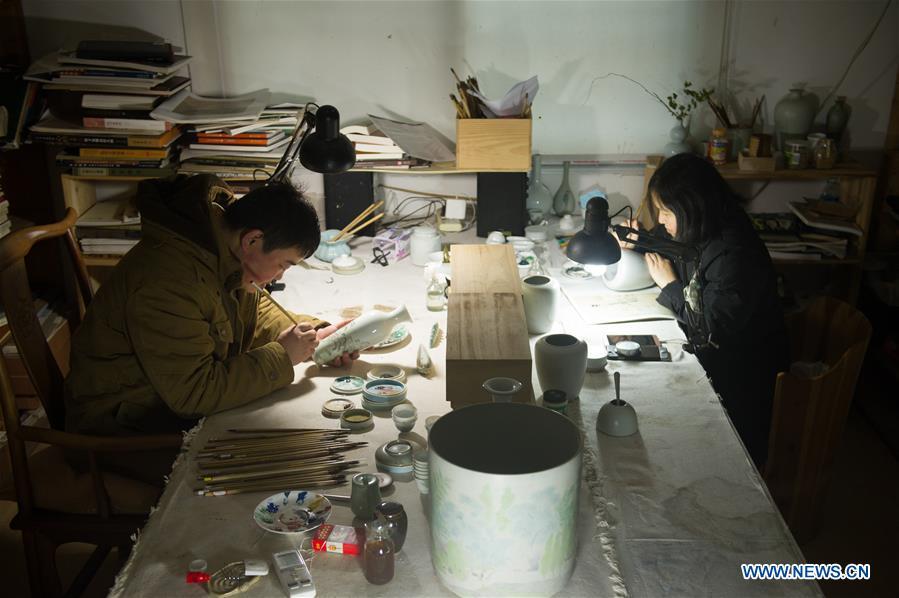 Artists Xiang Zhengyi (L) and Li Caixia create traditional literati paintings on porcelains at the workshop in Jingdezhen, east China\'s Jiangxi Province, Dec. 23, 2016. (Xinhua/Weng Xinyang)