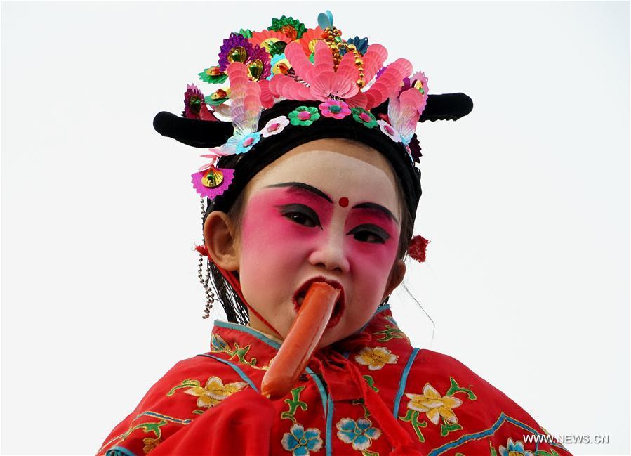 A little actor eats during the break of Shehuo performance at a temple fair in Junxian County, central China\'s Henan Province, Feb. 11, 2017. Shehuo is a folk entertainment popular in China. It can be traced back to ancient rituals to worship the earth, which people believe could bring good harvests and fortunes in return. (Xinhua/Li An)