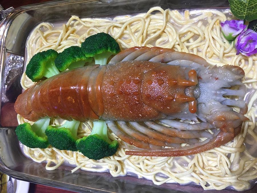 Emerald steamed lobster on noodles by carving master Zou Wantong.  (Photo/China Daily)