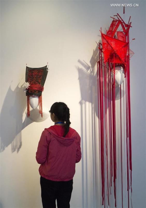 A visitor looks at hats on display at young Chinese designer Sui Yida\'s solo exhibition Masks of Personalities at the Art Museum in Nanjing University of Arts, April 8, 2017.  (Xinhua/Wang Xin)