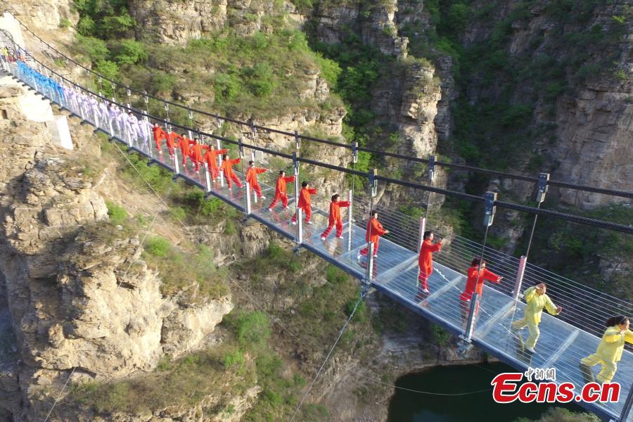 More than 200 enthusiasts perform Taichi on a suspended glass bridge at a scenic area in Fangshan District, Beijing, April 23, 2017. The performance was organized to mark Taichi Day, which is celebrated on the last Saturday in April. (Photo: China News Service/Zhong Xin)