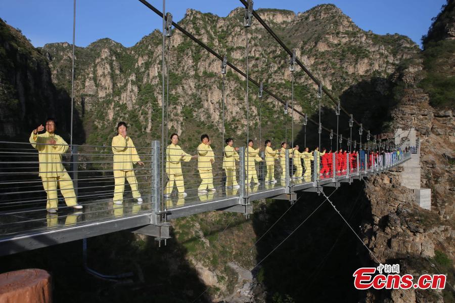More than 200 enthusiasts perform Taichi on a suspended glass bridge at a scenic area in Fangshan District, Beijing, April 23, 2017. The performance was organized to mark Taichi Day, which is celebrated on the last Saturday in April. (Photo: China News Service/Zhong Xin)