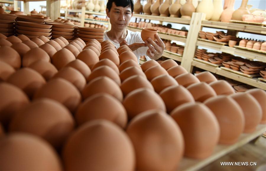 Intangible cultural heritage inheritor Feng Shaoxing checks an unburned earthenware at a workshop at Jingdezhen, east China\'s Jiangxi Province, June 26, 2017. Jingdezhen has a history of porcelain-making that dates back more than 1,000 years. In the late Ming Dynasty (1368-1644), it was not only the home of imperial kilns, but also a center for porcelain exports. (Xinhua/Song Zhenping)