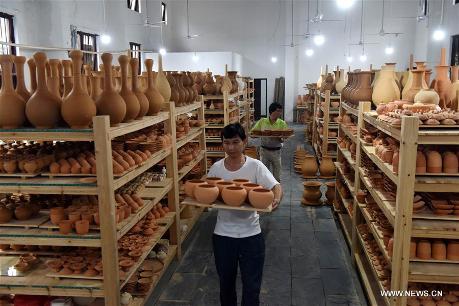Intangible cultural heritage inheritor Feng Shaoxing carries unburned earthenwares at a workshop at Jingdezhen, east China\'s Jiangxi Province, June 26, 2017. Jingdezhen has a history of porcelain-making that dates back more than 1,000 years. In the late Ming Dynasty (1368-1644), it was not only the home of imperial kilns, but also a center for porcelain exports. (Xinhua/Zhang Ruiqi)