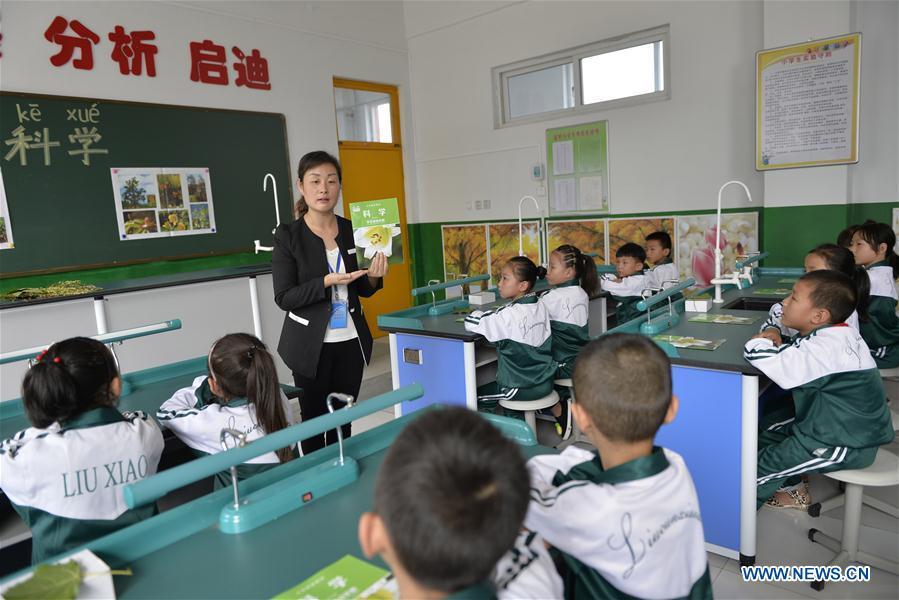 Science teacher Song Lihong introduces plants to first-year students at Liucun Primary School in Liucun Village of Xingtai City, north China\'s Hebei Province, Aug. 31, 2017. Since the beginning of this semester, primary schools across China have started to offer the science course to the first-year students. (Xinhua/Chen Lei)