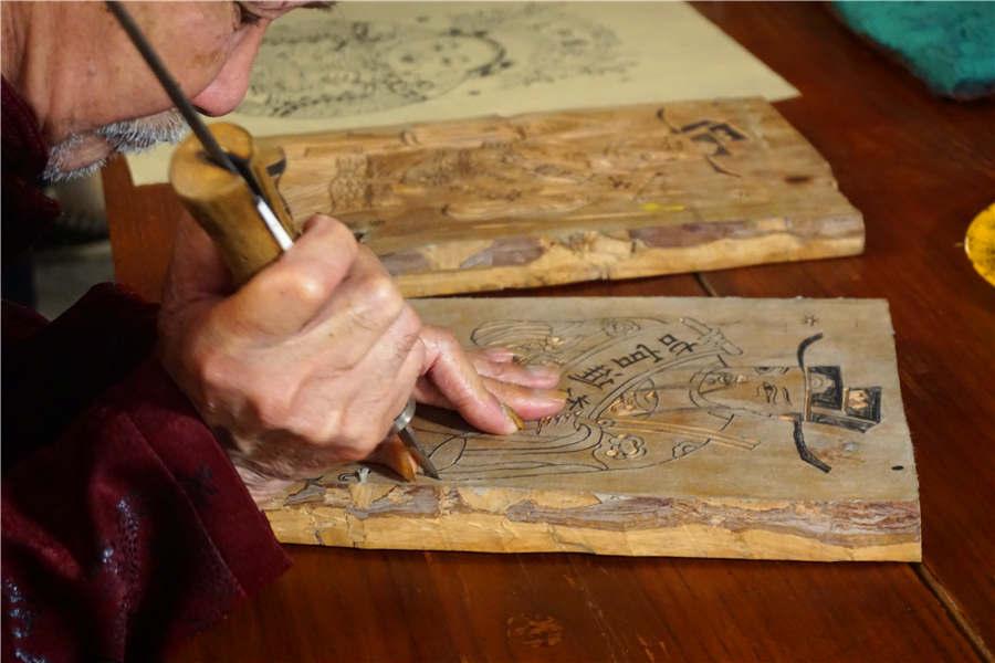 Chen Yiwen carves on a woodblock in his workshop in Laohekou county, Xiangyang city, Hubei Province, Sept. 25, 2017. (Photo/chinadaily.com.cn)
Chen Yiwen, who celebrated his 88th birthday on Monday, is the only surviving artist who has a high artistic attainment in wood engraving painting in Hubei province.
Chen is a national-level inheritor of Laohekou wood engraving New Year painting, which originated in the middle of the Ming Dynasty (1368-1644), and thrived during the Qianlong Period of the Qing Dynasty (1644-1911).
The whole process of wood engraving painting mainly includes the following steps: selecting material, sketching on paper, engraving on the woodblock, printing, coloring and drying. The theme of the painting covers figures from ancient history or legends, door gods and others.
Chen\'s works, with bright colors and meticulous lines, still maintain the authentic local features and folk flavors. One of Chen\'s wood engraving paintings was selected for the art textbook for middle school students in Hubei, and his works have also been exhibited around the country, as well as in Russia and Italy.
Chen started to learn the handicraft at 14 years old and began his own creation at 16. From Chen\'s grandfather to his father, the technique of wood engraving painting was passed down in the family, and now Chen\'s grandson has also inherited the handicraft.
During the thriving times of the painting, when people still kept the tradition of pasting New Year paintings in their houses and there was still no machine replacing manual work, Chen\'s family\'s workshop was always bustling and hustling.
But now, few people still use the handmade wood engraving New Year paintings, according to Chen, and the technique is gradually disappearing.
To better inherit the technique, training classes have been opened by Chen, and each year around 30 students took part in the training. The Laohekou wood engraving New Year painting was listed within the national-level intangible cultural heritage list in 2011. Currently, Xiangyang city in Hubei province has eight national-level intangible cultural heritages, 30 provincial-level items, and 83 city-level items.