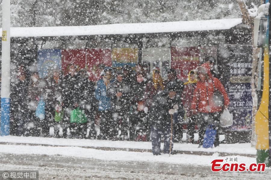 Pedestrians walk amid snowfall in Yantai, east China\'s Shandong Province, Dec. 11, 2017. A cold wave brought a heavy snowfall here. (Photo/VCG)