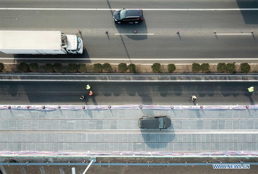 A car runs on a solar expressway in Jinan, capital of east China\'s Shandong Province, Dec. 22, 2017. China on Thursday opened a 1-km section solar expressway for testing. Solar panels are laid beneath part of a ring road surrounding Jinan. The road surface is made of a transparent, weight-bearing material that allows sunlight to penetrate. The panels, covering 5,875 square meters, can generate 1 million kwh of power in a year, enough to meet the everyday demand of around 800 households.(Xinhua/Zhu Zheng)