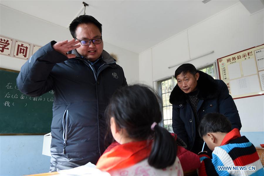 Newcome teacher Ouyang Qingchuan (1st L) gives a class to pupils under guidance of Tan Zeguang (R) at the Gaoshan Village Primary School in Tonggu Township of southwest China\'s Chongqing Municipality, Jan. 8, 2018. Tan Zeguang, a rural teacher of Gaoshan Village Primary School, has been teaching students in this remote area for a total of 40 years. Tan has to take care of both courses and daily life of students when they are at school, which is more than five kilometers away from the nearest town. In the past 40 years, more than 500 children were ever taught by Tan. As more students choose to attend better schools in towns, the school in which Tan stays has fewer students. But Tan still sticks to his post despite reaching retirement age. To his comfort, two young teachers have come to teach at the school and will continue his teaching career. (Xinhua/Tang Yi)