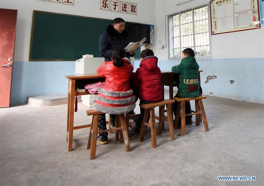 Tan Zeguang gives a class to three pupils of the first grade at the Gaoshan Village Primary School in Tonggu Township of southwest China\'s Chongqing Municipality, Jan. 8, 2018. Tan Zeguang, a rural teacher of Gaoshan Village Primary School, has been teaching students in this remote area for a total of 40 years. Tan has to take care of both courses and daily life of students when they are at school, which is more than five kilometers away from the nearest town. In the past 40 years, more than 500 children were ever taught by Tan. As more students choose to attend better schools in towns, the school in which Tan stays has fewer students. But Tan still sticks to his post despite reaching retirement age. To his comfort, two young teachers have come to teach at the school and will continue his teaching career. (Xinhua/Tang Yi)