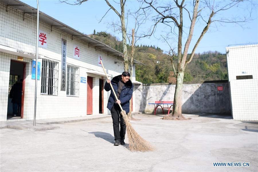 Tan Zeguang sweeps the yard at the Gaoshan Village Primary School in Tonggu Township of southwest China\'s Chongqing Municipality, Jan. 8, 2018. Tan Zeguang, a rural teacher of Gaoshan Village Primary School, has been teaching students in this remote area for a total of 40 years. Tan has to take care of both courses and daily life of students when they are at school, which is more than five kilometers away from the nearest town. In the past 40 years, more than 500 children were ever taught by Tan. As more students choose to attend better schools in towns, the school in which Tan stays has fewer students. But Tan still sticks to his post despite reaching retirement age. To his comfort, two young teachers have come to teach at the school and will continue his teaching career. (Xinhua/Tang Yi)