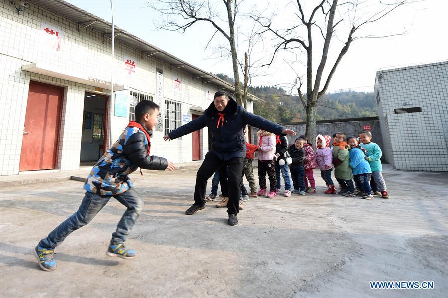 Tan Zeguang (2nd L) plays with students at the Gaoshan Village Primary School in Tonggu Township of southwest China\'s Chongqing Municipality, Jan. 8, 2018. Tan Zeguang, a rural teacher of Gaoshan Village Primary School, has been teaching students in this remote area for a total of 40 years. Tan has to take care of both courses and daily life of students when they are at school, which is more than five kilometers away from the nearest town. In the past 40 years, more than 500 children were ever taught by Tan. As more students choose to attend better schools in towns, the school in which Tan stays has fewer students. But Tan still sticks to his post despite reaching retirement age. To his comfort, two young teachers have come to teach at the school and will continue his teaching career. (Xinhua/Tang Yi)
