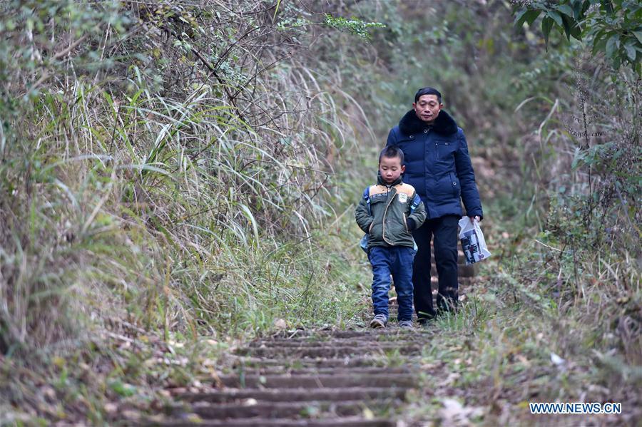 Tan Zeguang walks with a student on a mountain path to the Gaoshan Village Primary School in Tonggu Township of southwest China\'s Chongqing Municipality, Jan. 8, 2018. Tan Zeguang, a rural teacher of Gaoshan Village Primary School, has been teaching students in this remote area for a total of 40 years. Tan has to take care of both courses and daily life of students when they are at school, which is more than five kilometers away from the nearest town. In the past 40 years, more than 500 children were ever taught by Tan. As more students choose to attend better schools in towns, the school in which Tan stays has fewer students. But Tan still sticks to his post despite reaching retirement age. To his comfort, two young teachers have come to teach at the school and will continue his teaching career. (Xinhua/Tang Yi)