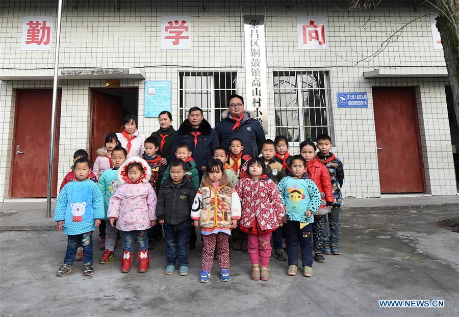 Tan Zeguang (C) poses for photo with his students and colleagues at the Gaoshan Village Primary School in Tonggu Township of southwest China\'s Chongqing Municipality, Jan. 8, 2018. Tan Zeguang, a rural teacher of Gaoshan Village Primary School, has been teaching students in this remote area for a total of 40 years. Tan has to take care of both courses and daily life of students when they are at school, which is more than five kilometers away from the nearest town. In the past 40 years, more than 500 children were ever taught by Tan. As more students choose to attend better schools in towns, the school in which Tan stays has fewer students. But Tan still sticks to his post despite reaching retirement age. To his comfort, two young teachers have come to teach at the school and will continue his teaching career. (Xinhua/Tang Yi)