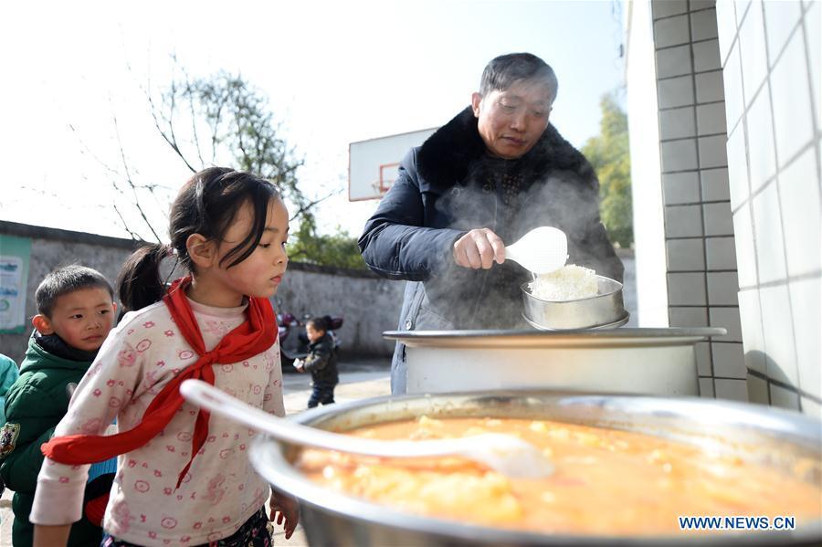 Tan Zeguang (R) prepares lunch for students at the Gaoshan Village Primary School in Tonggu Township of southwest China\'s Chongqing Municipality, Jan. 8, 2018. Tan Zeguang, a rural teacher of Gaoshan Village Primary School, has been teaching students in this remote area for a total of 40 years. Tan has to take care of both courses and daily life of students when they are at school, which is more than five kilometers away from the nearest town. In the past 40 years, more than 500 children were ever taught by Tan. As more students choose to attend better schools in towns, the school in which Tan stays has fewer students. But Tan still sticks to his post despite reaching retirement age. To his comfort, two young teachers have come to teach at the school and will continue his teaching career. (Xinhua/Tang Yi)