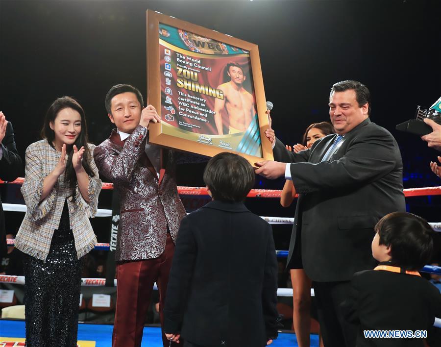 China\'s boxer Zou Shiming (C) receives the certification of Ambassador of Peace and Concordance presented by Mauricio Sulaiman, the President of the World Boxing Council (WBC) in Los Angeles, the United States, Feb. 24, 2018. Zou received Award of Honor and the title of Ambassador of Peace and Concordance by WBC here Saturday. (Xinhua/Li Ying)