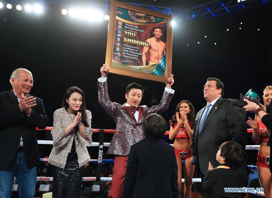 China\'s boxer Zou Shiming (C) holds the certification of Ambassador of Peace and Concordance presented by Mauricio Sulaiman, the President of the World Boxing Council (WBC) in Los Angeles, the United States, Feb. 24, 2018. Zou received Award of Honor and the title of Ambassador of Peace and Concordance by WBC here Saturday. (Xinhua/Li Ying)