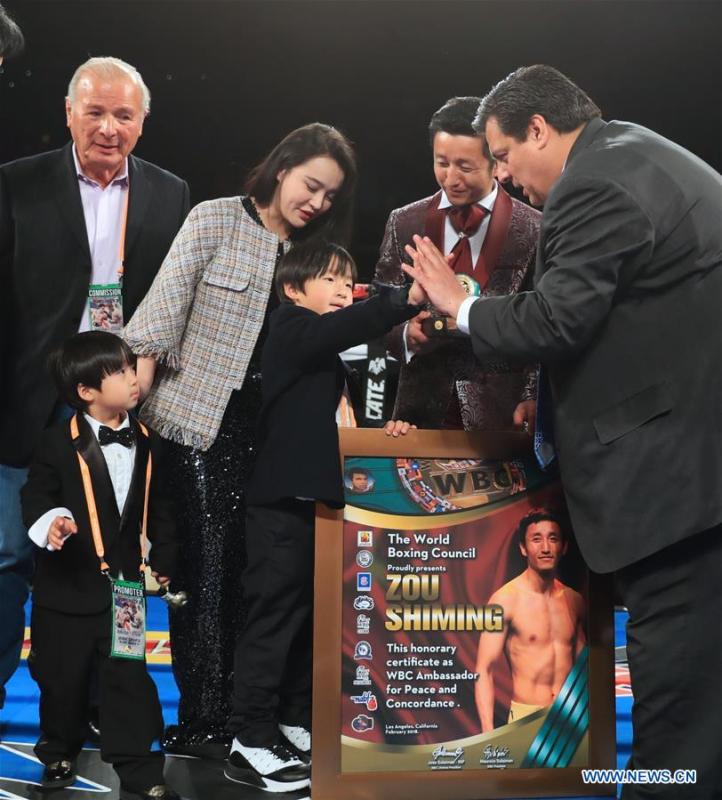 Zou Mingxuan (Front, L), son of China\'s boxer Zou Shiming is greeted by Mauricio Sulaiman(Front, R), the President of the World Boxing Council (WBC) during Zou Shiming\'s awarding ceremony in Los Angeles, the United States, Feb. 24, 2018. Zou received Award of Honor and the certification of Ambassador of Peace and Concordance by WBC here Saturday. (Xinhua/Li Ying)