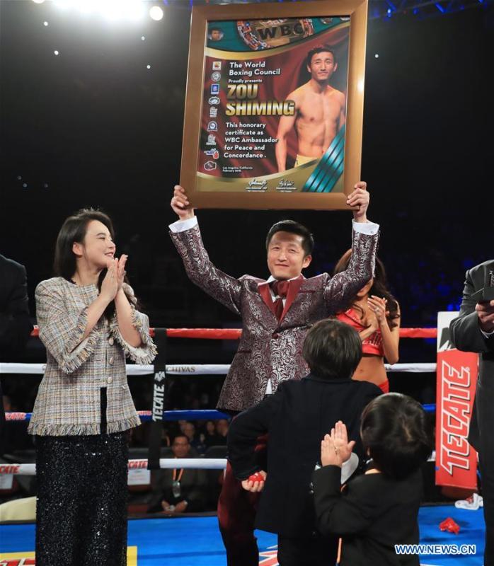 China\'s boxer Zou Shiming (Top, R) holds the certification of Ambassador of Peace and Concordance presented by Mauricio Sulaiman, the President of the World Boxing Council (WBC) in Los Angeles, the United States, Feb. 24, 2018. Zou received Award of Honor and the title of Ambassador of Peace and Concordance by WBC here Saturday. (Xinhua/Li Ying)