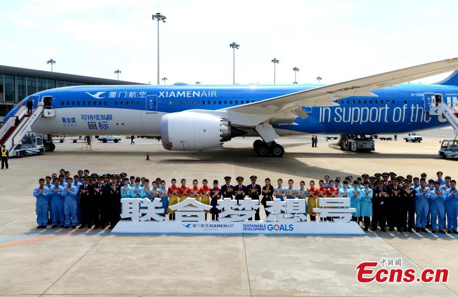 Flight crews and ground service members pose for a photo in front of a Xiamen Airlines plane, in Fuzhou City, the capital of East China\'s Fujian Province, March 21, 2018. In an effort to create more awareness about the goals, the airline painted the exterior of one of its aircraft with the theme, a first for the airlines industry. The two sides signed the agreement at the UN headquarters in New York to underscore the airlines\' commitment to supporting the new development agenda on Feb. 15, 2017. (Photo: China News Service/Wang Dongming)