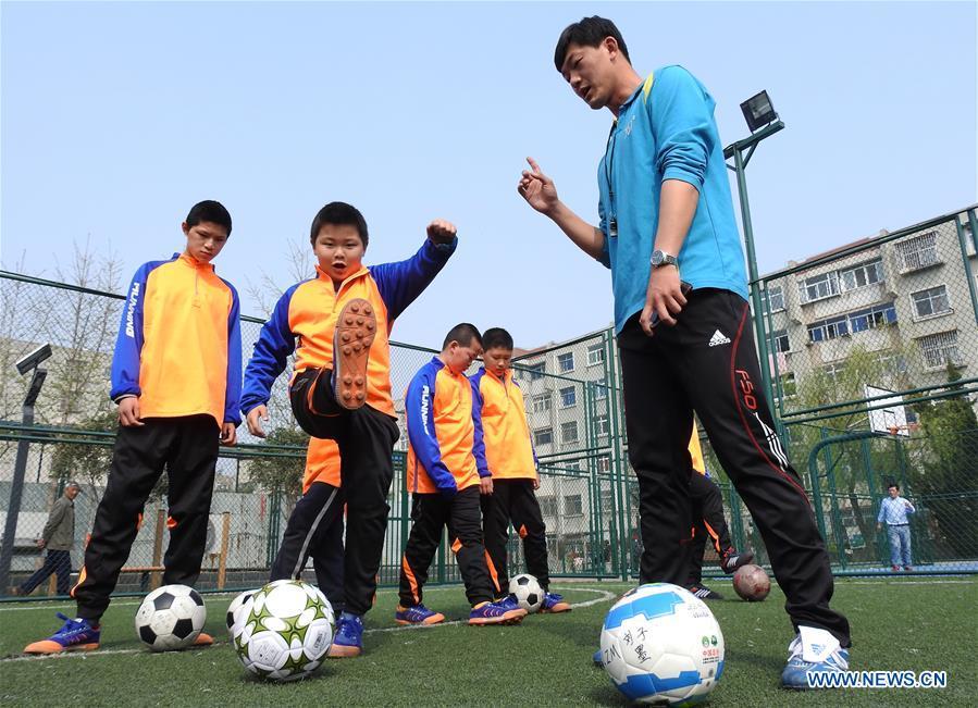 A coach directs autistic children to play football on the football field at Xinnan Community in Lianyungang City, east China\'s Jiangsu Province, April 1, 2018. A football team, composed of 22 autistic children aging from 7 to 16, was jointly set up by the community and an autism care center ahead of the World Autism Awareness Day, which falls on April 2 every year. The football team will have trainings and games every week. (Xinhua/Geng Yuhe)