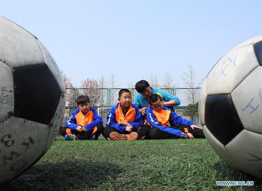A football coach stays with autistic children on the football field at Xinnan Community in Lianyungang City, east China\'s Jiangsu Province, April 1, 2018. A football team, composed of 22 autistic children aging from 7 to 16, was jointly set up by the community and an autism care center ahead of the World Autism Awareness Day, which falls on April 2 every year. The football team will have trainings and games every week. (Xinhua/Geng Yuhe)