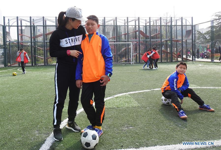 A football coach talks with an autistic child on the football field at Xinnan Community in Lianyungang City, east China\'s Jiangsu Province, April 1, 2018. A football team, composed of 22 autistic children aging from 7 to 16, was jointly set up by the community and an autism care center ahead of the World Autism Awareness Day, which falls on April 2 every year. The football team will have trainings and games every week. (Xinhua/Geng Yuhe)