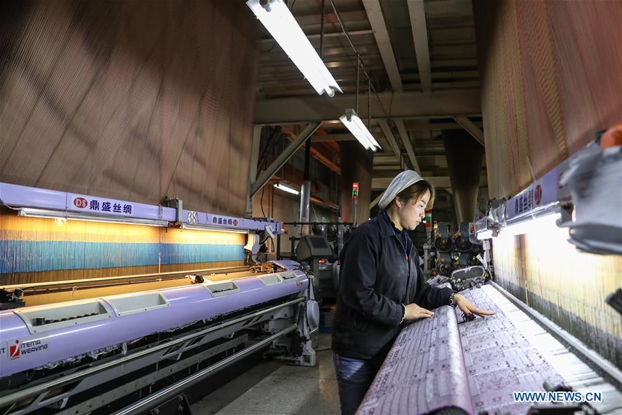 A worker checks the working of a modern weaving machine for Song brocade at the Wujiang Dingsheng Silk Company in Shengze Town, Suzhou City of east China\'s Jiangsu Province, March 31, 2018. Song brocade, dating back to the Song Dynasty (960-1127) in ancient China, was listed as the World Intangible Cultural Heritage in 2009. Dedicated in inheriting and developing of Song brocade, the Wujiang Dingsheng Silk Company has applied the brocade to the making of products such as bags, boxes, clothing and handicrafts. (Xinhua/Yang Lei)