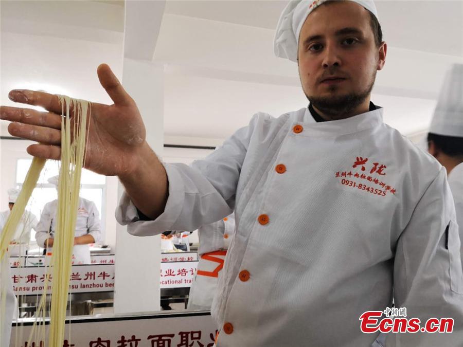 A man from Kazakhstan shows many strands of thin, long noodle he made at a workshop in Lanzhou City, Northwest China\'s Gansu Province. Some foreigners from Spain, Germany, Bangladesh and Kazakhstan learned about making Lanzhou Lamian to understand Chinese culture. Lamian is made by repeatedly twisting, stretching and folding the dough into strands at various lengths and thicknesses. (Photo: China News Service/Shi Jingjing)