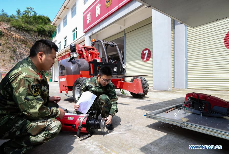 Fire services officer Jiang Yuhang (R) and technician Wang Gang check the firefighting equipment in Kaili City, southwest China\'s Guizhou Province, May 8, 2018. On May 17, 2008, Jiang, a 20-year-old highway administration employee, was extricated by firefighters, 123 hours after he was trapped in the rubble at quake-hit Yingxiu Township of Wenchuan County, southwest China\'s Sichuan Province. Jiang was a survivor of the 8.0-magnitude earthquake that struck Sichuan\'s Wenchuan County on May 12, 2008. The quake left more than 69,000 dead, 374,000 injured, 18,000 missing and millions homeless. Jiang said it were firefighters who gave him the second life, and he desired to be a soldier like them. At the end of 2008, Jiang realized his dream to join the army and served in the group who once saved him. After training for half a year, he finally became a real fire soldier in Shanghai in 2009. Jiang later got promoted to the position of an officer, and in March this year, he was transferred to the firefighting force in his hometown Kaili City, southwest China\'s Guizhou Province. In the past ten years, the young man, who was saved in that catastrophic earthquake, saved more people\'s lives with his own efforts. (Xinhua/Jiang Hongjing)