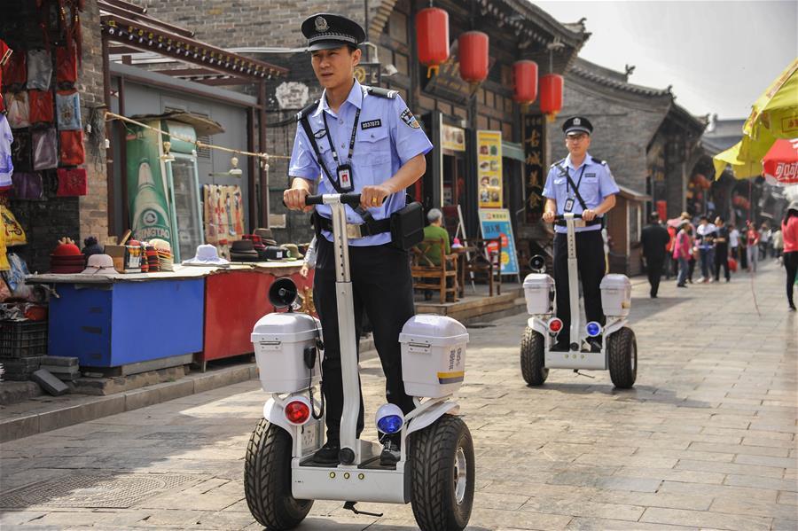 Two police officers ride Segway-like self-balancing scooters as they patrol a street in the Pingyao Ancient City, a popular tourist destination, in Jinzhong, north China\'s Shanxi Province, May 13, 2018. (Xinhua/Liang Shengren)