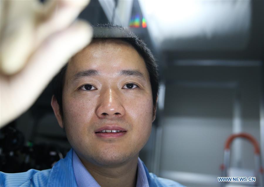 Jin Xianmin, a quantum communication researcher with Shanghai Jiaotong University, checks a photonic quantum chip in Shanghai, east China, May 15, 2018. Chinese scientists demonstrated the first two-dimensional quantum walks of single photons in real spatial space, which may provide a powerful platform to boost analog quantum computing. They reported in a paper published in the journal Science Advances a three-dimensional photonic chip with a scale up to 49-multiply-49 nodes, by using a technique called femtosecond direct writing. (Xinhua/Ding Ting)