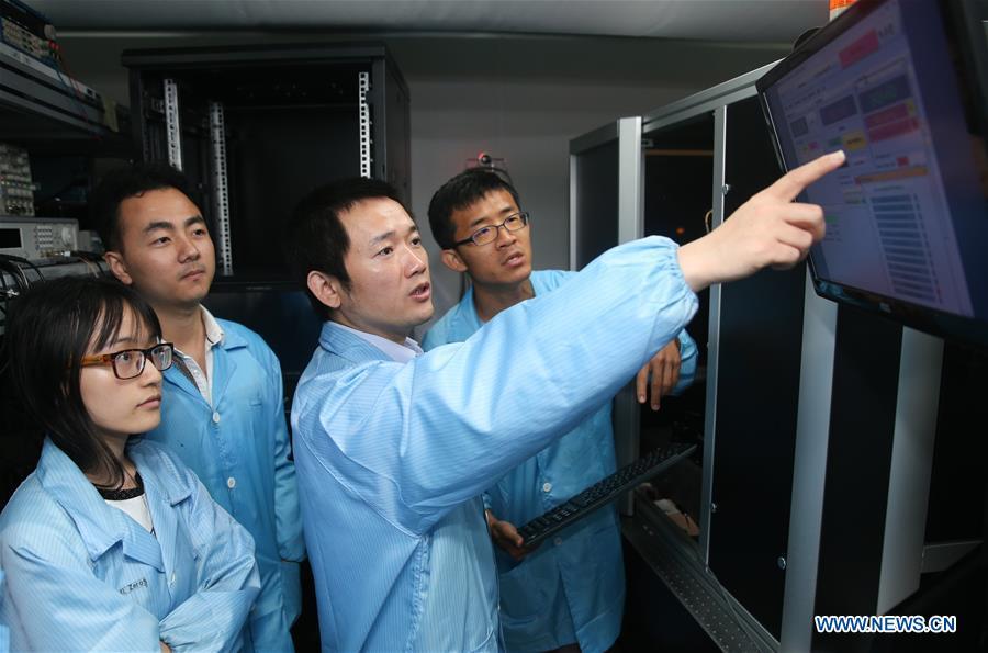 Jin Xianmin (2nd R), a quantum communication researcher with Shanghai Jiaotong University, instructs students in making photonic quantum chip in Shanghai, east China, May 15, 2018. Chinese scientists demonstrated the first two-dimensional quantum walks of single photons in real spatial space, which may provide a powerful platform to boost analog quantum computing. They reported in a paper published in the journal Science Advances a three-dimensional photonic chip with a scale up to 49-multiply-49 nodes, by using a technique called femtosecond direct writing. (Xinhua/Ding Ting)