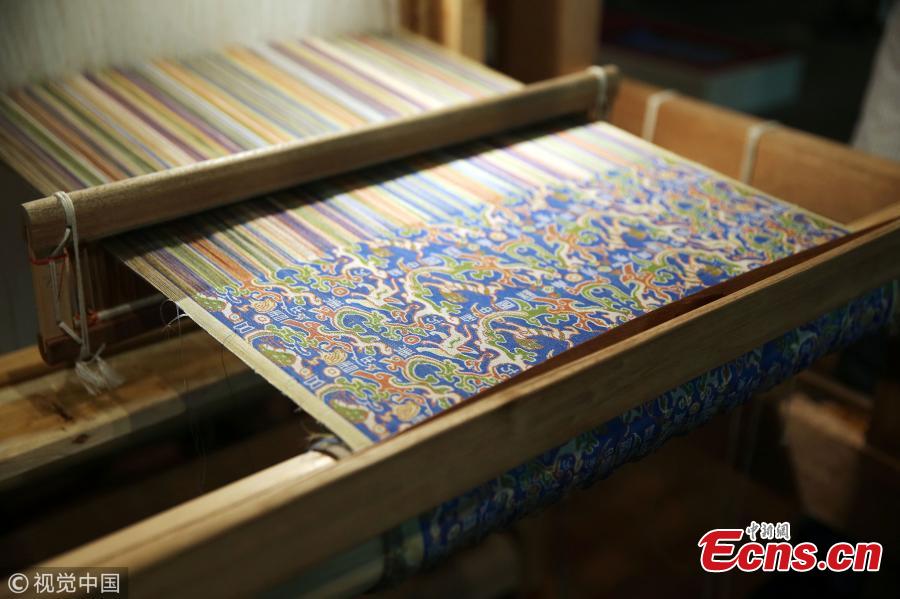 A replica of a colorful brocade embroidered with the text “Wuxing Chu Dongfang Li Zhongguo”, which literary means \