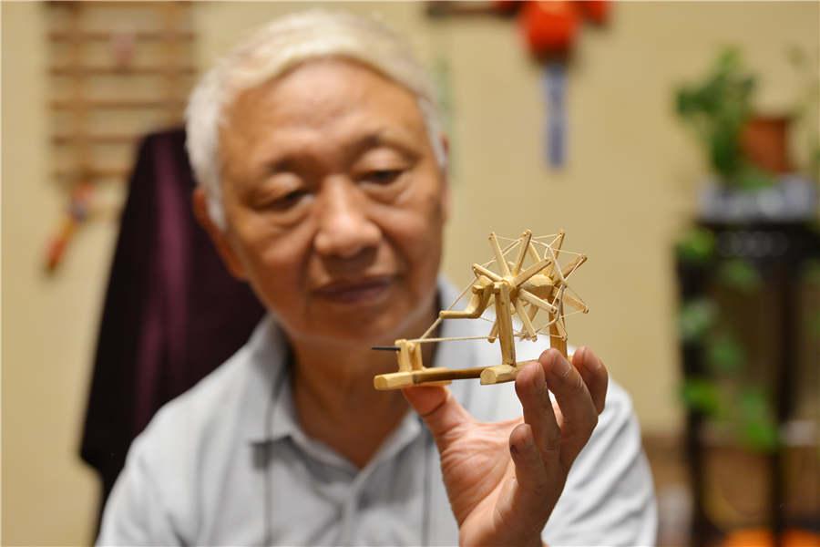 Chen Hesheng shows a miniature wooden spinning wheel. (Photo/Asianewsphoto)