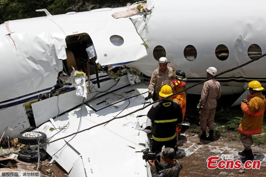 Firefighters stand near a Gulfstream G200 aircraft that skidded off the runway during landing at Toncontin International Airport in Tegucigalpa, Honduras, May 22, 2018. At least six passengers were injured. (Photo/Agencies)