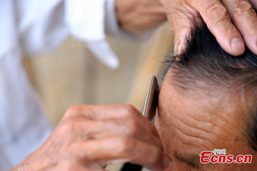 Barber Hu Daofa cuts a man’s hair at a village in Zhuangbu Countryside, Huichang County, East China’s Jiangxi Province. Hu, 73, started travelling around nearby villages offering door-to-door haircutting, shaving, and ear-cleaning in 1966, charging an annual fee of 130 yuan for three visits a month. Hu can’t ride a bicycle, so he walks. Most of his customers are children and elderly people. (Photo: China News Service/Jiang Tao)