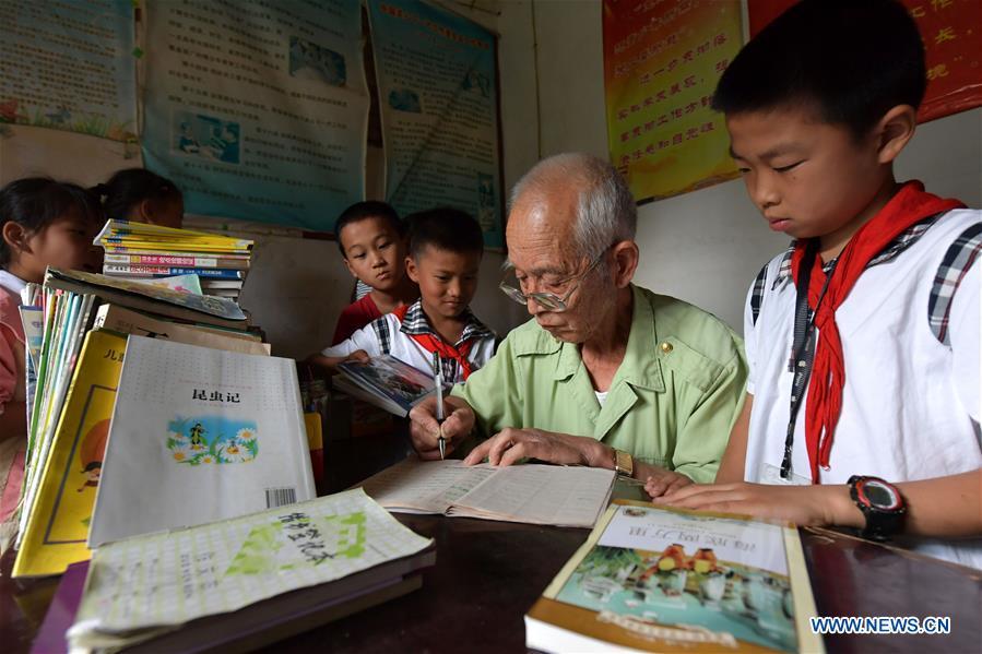 Children borrow books from the caring station for left-behind children at Miao Yanxiang\'s home in Shibu Town, Nanchang City of east China\'s Jiangxi Province, May 23, 2018. Miao, over 70, established a caring station for left-behind children at his own house in 2009, where he provided free place for children to do homework and study after school. Having received more than 3,000 children over the past nine years, Miao is satisfied with his voluntary work as he see the progress of the children. (Xinhua/Peng Zhaozhi)