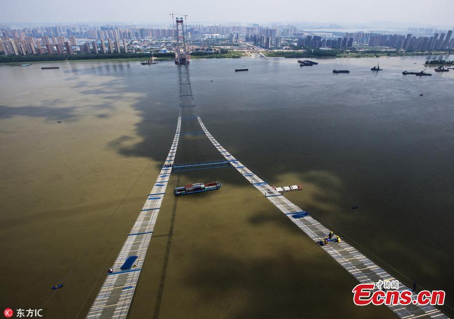 Chinese workers build a bridge over the Yangtze River in Wuhan, capital of central China\'s Hubei Province, May 23, 2018. The bridge stretches in the air, looking like \