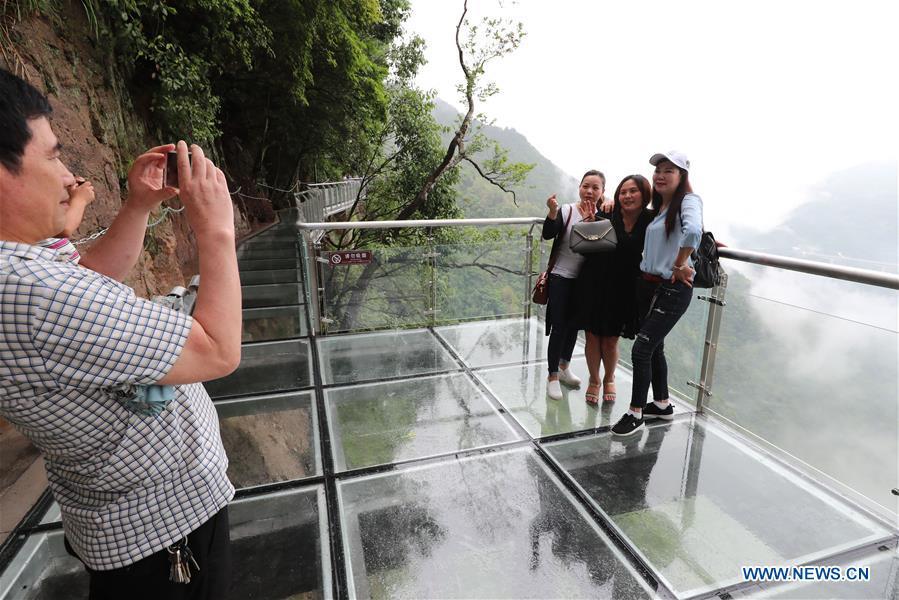 People pose for photos on the Lingyundu glass trestle in the Xuedou Mountain in Ningbo City, east China\'s Zhejiang Province, May 26, 2018. The glass trestle was opened to tourists on Saturday. (Xinhua/Zhang Peijian)