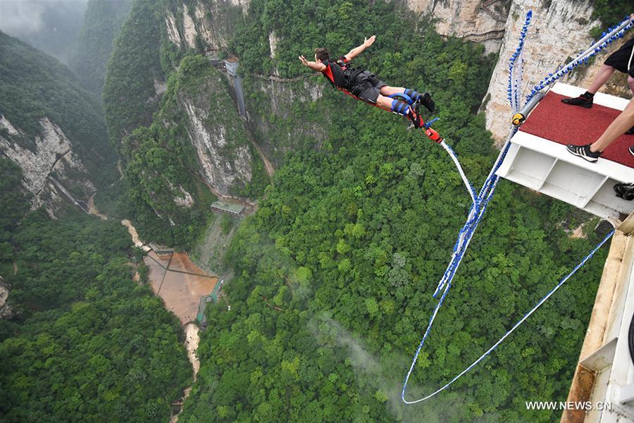 An enthusiast goes bungee jumping from Zhangjiajie Grand Canyon\'s glass-bottom bridge, during a challenge in Zhangjiajie scenic spot, central China\'s Hunan Province, May 26, 2018. Enthusiasts from Russia, Australia, Britain and other countries and regions participated in the challenge on Saturday. (Xinhua/Yan Yuan)