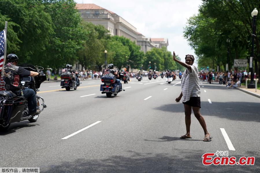 A woman waves at riders as thousands of military veterans and their supporters participate in the 31st annual Rolling Thunder motorcycle rally and Memorial Day weekend \