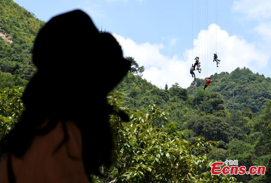 Extreme sports enthusiasts take on the challenge of descending from and then climbing back to a suspended glass bridge 188 meters above the ground at a scenic spot in Youxi County, East China’s Fujian Province, May 26, 2018. More than 20 participants fast-roped down and then climbed back up from under the bottom of the bridge. (Photo: China News Service/Wang Dongming)