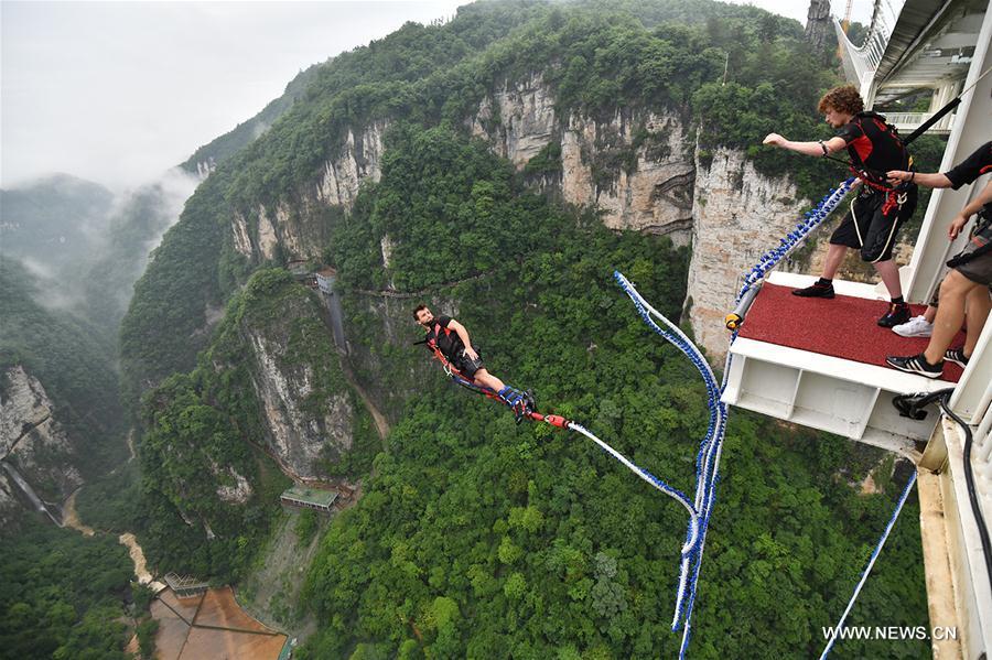 An enthusiast goes bungee jumping from Zhangjiajie Grand Canyon\'s glass-bottom bridge, during a challenge in Zhangjiajie scenic spot, central China\'s Hunan Province, May 26, 2018. Enthusiasts from Russia, Australia, Britain and other countries and regions participated in the challenge on Saturday. (Xinhua/Yan Yuan)
